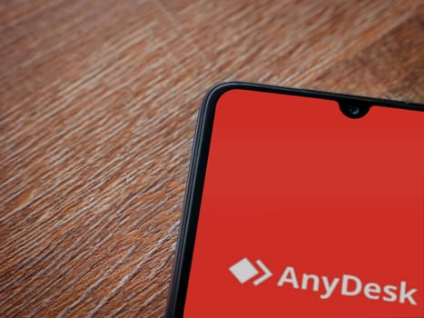 Lod, Israel - July 16,2023: Anydesk app launch screen on smartphone on wooden background. Top view flat lay with copy space.