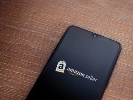 Lod, Israel - July 16,2023: Amazon Seller app launch screen on smartphone on wooden background. Top view flat lay with copy space.