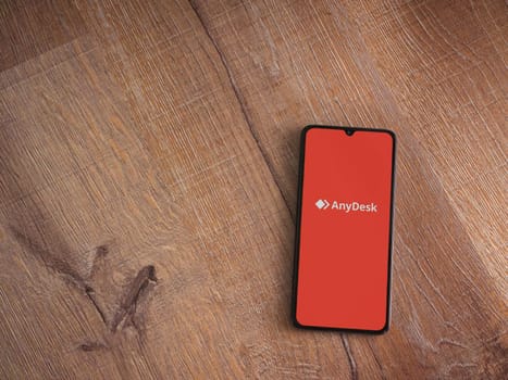 Lod, Israel - July 16,2023: Anydesk app launch screen on smartphone on wooden background. Top view flat lay with copy space.
