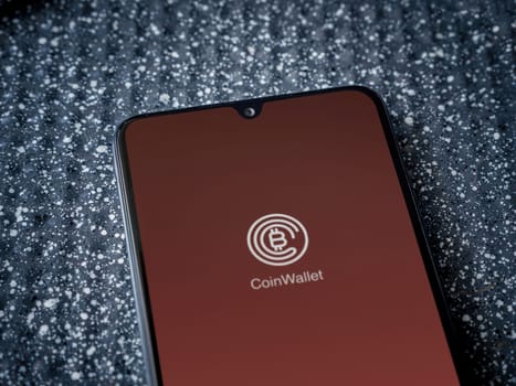Lod, Israel - July 16,2023: CoinWallet app launch screen on smartphone on metallic background. Close up top view flat lay.