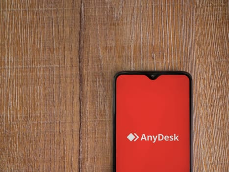 Lod, Israel - July 16,2023: Anydesk app launch screen on smartphone on wooden background. Top view flat lay with copy space.