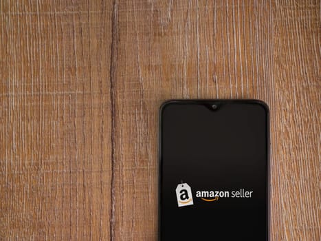 Lod, Israel - July 16,2023: Amazon Seller app launch screen on smartphone on wooden background. Top view flat lay with copy space.