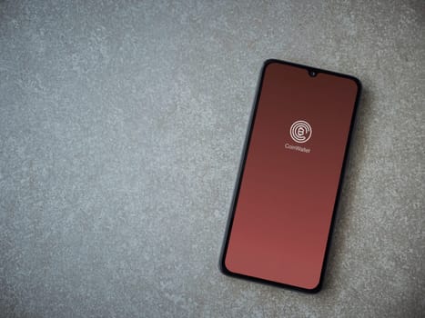 Lod, Israel - July 16,2023: CoinWallet app launch screen on smartphone on ceramic stone background. Top view flat lay with copy space.