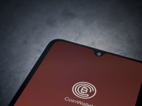 Lod, Israel - July 16,2023: CoinWallet app launch screen on smartphone on dark marble stone background. Top view flat lay with copy space.