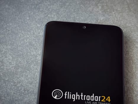 Lod, Israel - July 16,2023: Flightradar24 Flight Tracker app launch screen on smartphone on ceramic stone background. Top view flat lay with copy space.