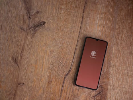 Lod, Israel - July 16,2023: CoinWallet app launch screen on smartphone on wooden background. Top view flat lay with copy space.
