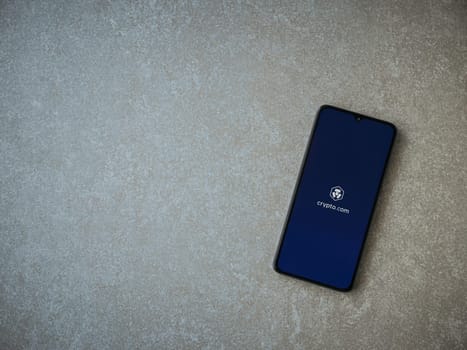 Lod, Israel - July 16,2023: Crypto.com app launch screen on smartphone on ceramic stone background. Top view flat lay with copy space.