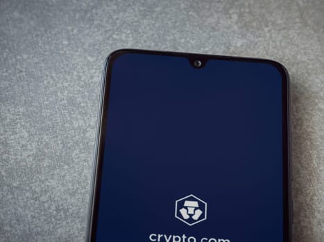 Lod, Israel - July 16,2023: Crypto.com app launch screen on smartphone on ceramic stone background. Top view flat lay with copy space.