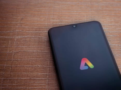 Lod, Israel - July 16,2023: Adobe Express - Graphic Design app launch screen on smartphone on wooden background.. Top view flat lay with copy space.