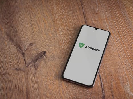 Lod, Israel - July 16,2023: AdGuard app launch screen on smartphone on wooden background. Top view flat lay with copy space.