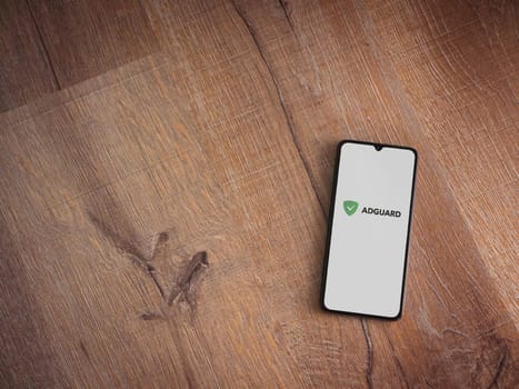 Lod, Israel - July 16,2023: AdGuard app launch screen on smartphone on wooden background. Top view flat lay with copy space.