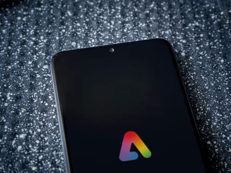 Lod, Israel - July 16,2023: Adobe Express - Graphic Design app launch screen on smartphone on metallic background. Close up top view flat lay.