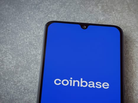 Lod, Israel - July 16,2023: Coinbase app launch screen on smartphone on ceramic stone background. Top view flat lay with copy space.