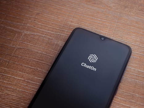 Lod, Israel - July 16,2023: ChatOn app launch screen on smartphone on wooden background. Top view flat lay with copy space.