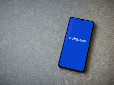 Lod, Israel - July 16,2023: Coinbase app launch screen on smartphone on ceramic stone background. Top view flat lay with copy space.