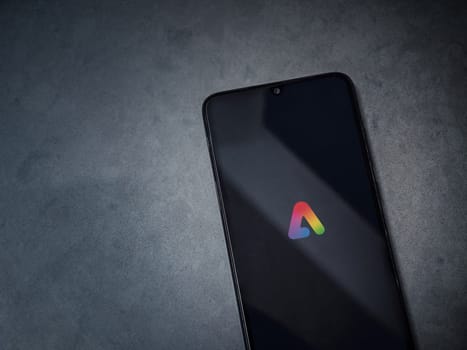 Lod, Israel - July 16,2023: Adobe Express - Graphic Design app launch screen on smartphone on dark marble stone background. Top view flat lay with copy space.