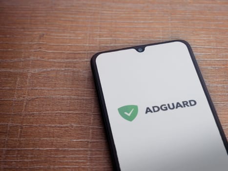 Lod, Israel - July 16,2023: AdGuard app launch screen on smartphone on wooden background. Top view flat lay with copy space.
