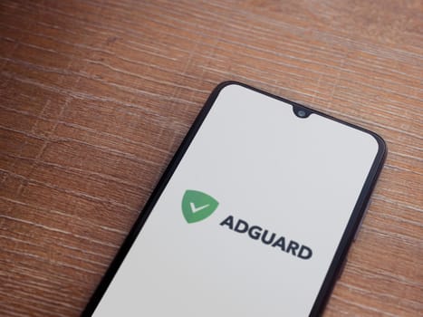 Lod, Israel - July 16,2023: AdGuard app launch screen on smartphone on wooden background. Top view flat lay with copy space.