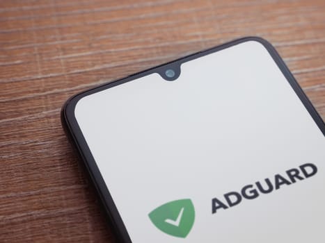 Lod, Israel - July 16,2023: AdGuard app launch screen on smartphone on wooden background. Top view flat lay with copy space.