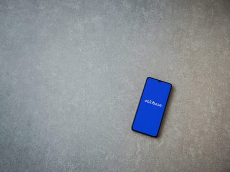 Lod, Israel - July 16,2023: Coinbase app launch screen on smartphone on ceramic stone background. Top view flat lay with copy space.