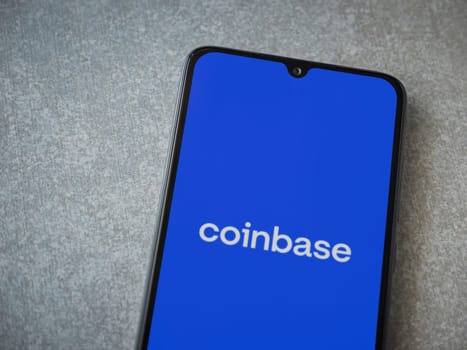 Lod, Israel - July 16,2023: Coinbase app launch screen on smartphone on ceramic stone background. Top view flat lay with copy space.