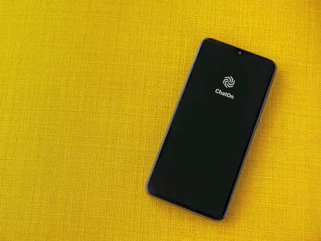 Lod, Israel - July 16,2023: ChatOn app launch screen on smartphone on yellow fabric background. Top view flat lay with copy space.