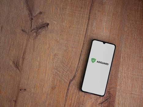 Lod, Israel - July 16,2023: AdGuard app launch screen on smartphone on wooden background. Top view flat lay with copy space.