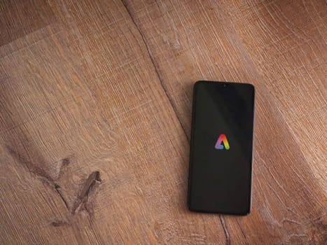 Lod, Israel - July 16,2023: Adobe Express - Graphic Design app launch screen on smartphone on wooden background.. Top view flat lay with copy space.