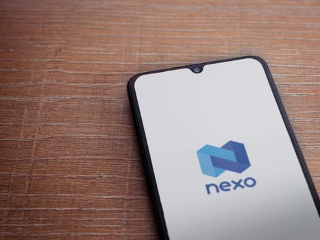 Lod, Israel - July 16,2023: Nexo app launch screen on smartphone on wooden background. Top view flat lay with copy space.