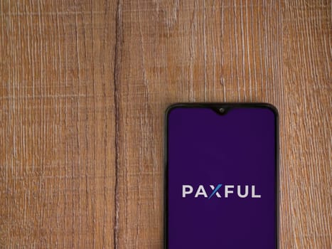 Lod, Israel - July 16,2023: Paxful app launch screen on smartphone on wooden background. Top view flat lay with copy space.