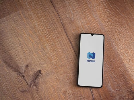 Lod, Israel - July 16,2023: Nexo app launch screen on smartphone on wooden background. Top view flat lay with copy space.