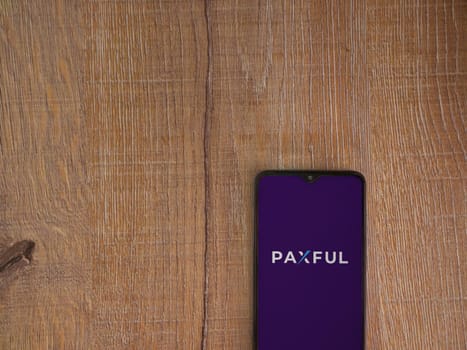 Lod, Israel - July 16,2023: Paxful app launch screen on smartphone on wooden background. Top view flat lay with copy space.