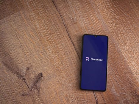 Lod, Israel - July 16,2023: PhotoRoom Studio Photo Editor app launch screen on smartphone on wooden background.. Top view flat lay with copy space.