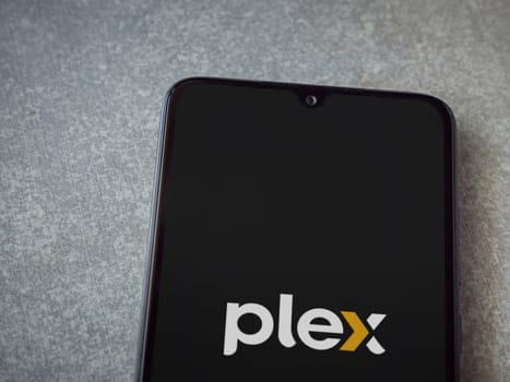 Lod, Israel - July 16,2023: Plex app launch screen on smartphone on ceramic stone background. Top view flat lay with copy space.