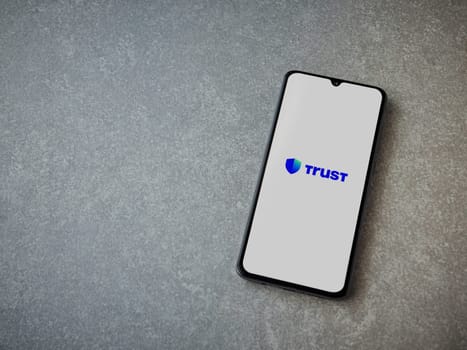 Lod, Israel - July 16,2023: Trust Wallet app launch screen on smartphone on ceramic stone background. Top view flat lay with copy space.