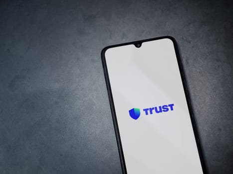 Lod, Israel - July 16,2023: Trust Wallet app launch screen on smartphone on dark marble stone background. Top view flat lay with copy space.