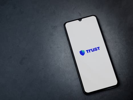 Lod, Israel - July 16,2023: Trust Wallet app launch screen on smartphone on dark marble stone background. Top view flat lay with copy space.