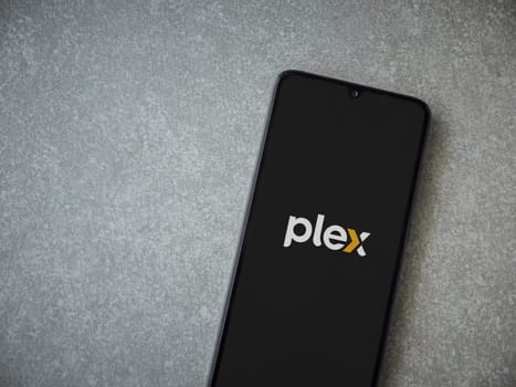Lod, Israel - July 16,2023: Plex app launch screen on smartphone on ceramic stone background. Top view flat lay with copy space.