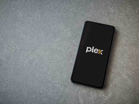 Lod, Israel - July 16,2023: Plex app launch screen on smartphone on ceramic stone background. Top view flat lay with copy space.