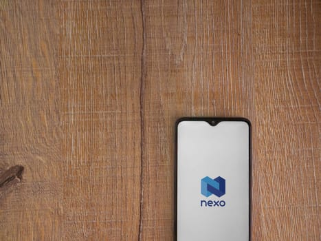 Lod, Israel - July 16,2023: Nexo app launch screen on smartphone on wooden background. Top view flat lay with copy space.