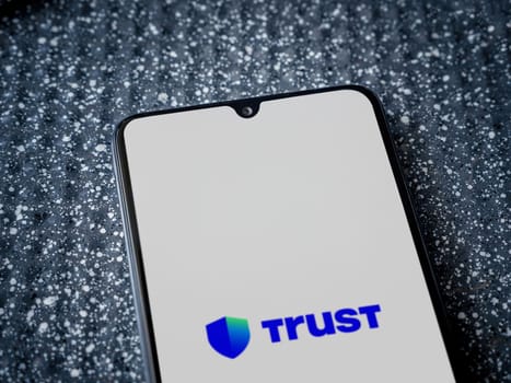 Lod, Israel - July 16,2023: Trust Wallet app launch screen on smartphone on metallic background. Close up top view flat lay.