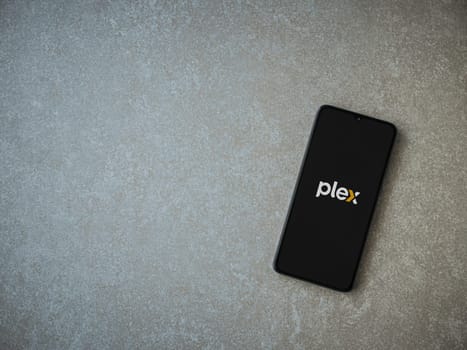 Lod, Israel - July 16,2023: Plex app launch screen on smartphone on ceramic stone background. Top view flat lay with copy space.