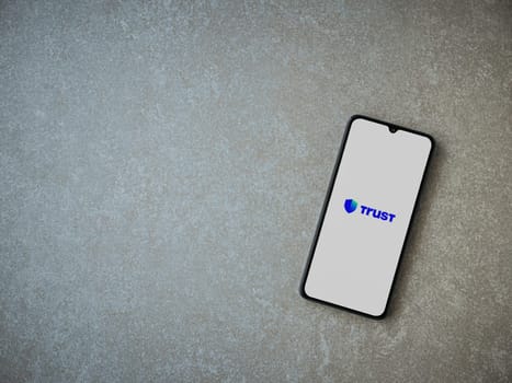 Lod, Israel - July 16,2023: Trust Wallet app launch screen on smartphone on ceramic stone background. Top view flat lay with copy space.