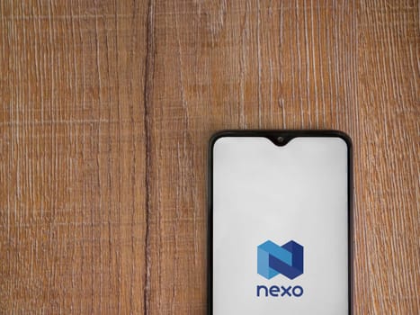 Lod, Israel - July 16,2023: Nexo app launch screen on smartphone on wooden background. Top view flat lay with copy space.