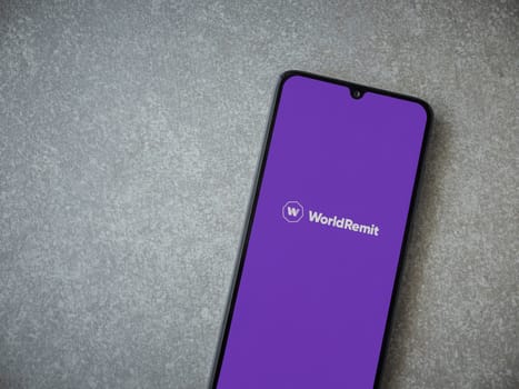 Lod, Israel - July 16,2023: WorldRemit app launch screen on smartphone on ceramic stone background. Top view flat lay with copy space.