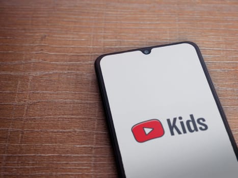 Lod, Israel - July 16,2023: YouTube Kids app launch screen on smartphone on wooden background. Top view flat lay with copy space.