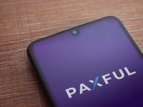 Lod, Israel - July 16,2023: Paxful app launch screen on smartphone on wooden background. Top view flat lay with copy space.