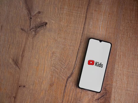 Lod, Israel - July 16,2023: YouTube Kids app launch screen on smartphone on wooden background. Top view flat lay with copy space.