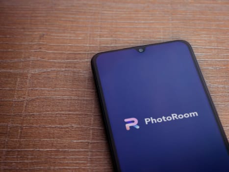 Lod, Israel - July 16,2023: PhotoRoom Studio Photo Editor app launch screen on smartphone on wooden background.. Top view flat lay with copy space.