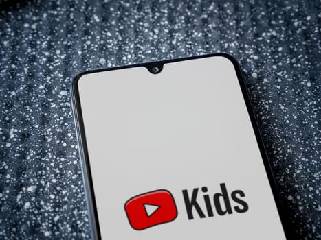 Lod, Israel - July 16,2023: YouTube Kids app launch screen on smartphone on metallic background. Close up top view flat lay.